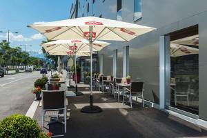 因斯布鲁克Tivoli Hotel Innsbruck的人行道上一排带遮阳伞的桌椅