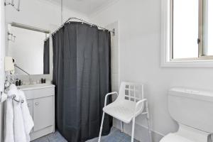 Port MoontaCostello Hotels - Moonta Bay Cabins的浴室设有黑色淋浴帘和椅子