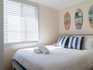 悉尼Amazing Views - 3 Bed Malabar的卧室配有白色床,墙上设有冲浪板