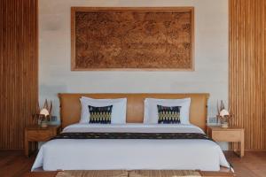 BumbangTUNAK Resort Lombok的一间卧室配有一张带白色床单的大床