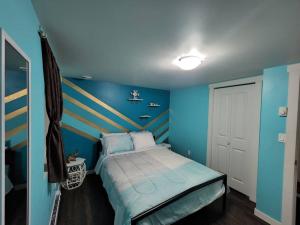 萨斯卡通TheAuroras: Vibrant&Cheerful 2 bdrm Stylish suite的蓝色卧室,配有带条纹床头板的床