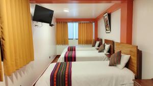 马丘比丘Amakonkay Machupicchu的酒店客房设有三张床和电视。