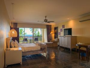 拉布安棕榈滩度假村的一间卧室配有一张床,客厅配有电视