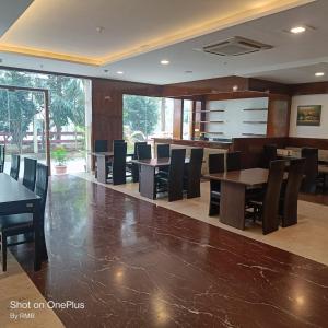 班加罗尔ASTRA HOTELS & SUITES WHITEFIELD NEAR TO NALLURAHALLI METRO STATION and KTPO的大楼内带桌椅的用餐室