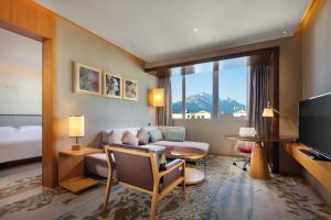 丽江丽江实力希尔顿花园酒店的一间配有沙发、一张桌子和一台电视的酒店客房