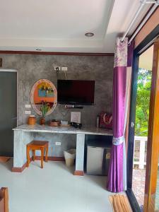 高兰Thai Smile Bungalows的客房设有一张书桌、一台电视和紫色窗帘