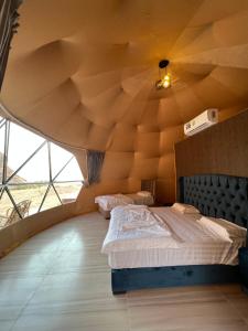 瓦迪拉姆Wadi Rum Mars Camp的一间卧室设有大型木制天花板和两张床