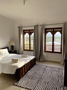 马斯喀特Jabal Sifah Marina View Apartment的一间卧室设有床、两个窗户和地毯。