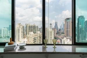 上海Shanghai Yi DU Apartments Downtown - near Nanjing West Road subway的窗户享有市景,配有两杯酒。