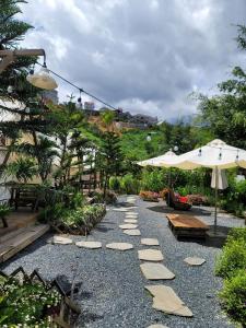 大叻Ma Lá Glamping Đà Lạt的花园中一条带岩石和遮阳伞的小路