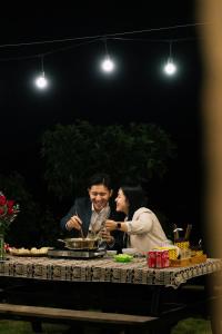 木州县Avatar Homestay & Coffee - Mộc Châu的坐在桌子上的男人和女人
