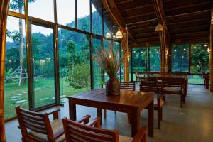Làng Hoa (2)The BanBa Jungle Lodge的用餐室配有桌椅和大窗户