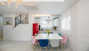 济州市Homechee Kids Poolvilla的一间设有白色桌子和粉红色椅子的用餐室