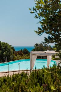 马里蒂玛Marenea Suite Hotel - CDSHotels的蓝色的游泳池,有白色的天篷和海洋
