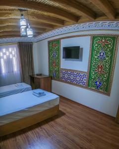 布哈拉Antique hotel Imran的一间卧室设有两张床,墙上配有电视。