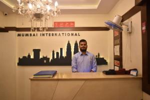 孟买Hotel Mumbai International- Near T2 International Airport的站在办公室柜台上的人