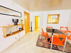 波朗特吕Apart'Hotel du Faubourg by Stay Swiss的一间带桌子和橙色椅子的用餐室