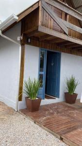 邦比尼亚斯cabana canto da maré的门廊,两盆植物和一扇蓝色门