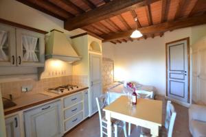 里帕尔贝拉Residence Borgo Felciaione的厨房配有白色橱柜、桌子和炉灶。