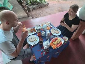 锡吉里亚sigiriya village hostel的坐在餐桌旁吃饭的男人和女人