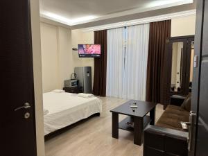 巴统Iko's Family Apartments的酒店客房配有床、沙发和电视。