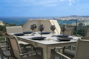 梅利哈Lux Sea&Country Views with Pool的一张带椅子的白色桌子和酒杯