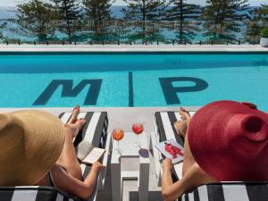 悉尼Manly Pacific Sydney MGallery Collection的两人坐在游泳池边的椅子上