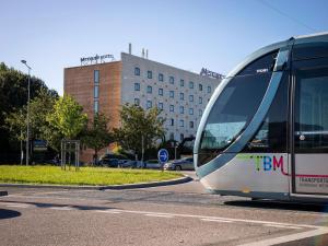 梅里尼亚克波尔多机场美居酒店的一辆公共汽车沿着城市的街道行驶
