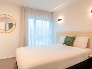 惠灵顿惠灵顿四中心美爵公寓式酒店的卧室设有一张白色大床和一扇窗户。