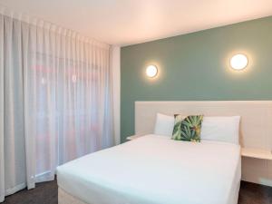 惠灵顿惠灵顿四中心美爵公寓式酒店的卧室配有白色的床和窗户。