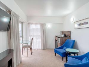 惠灵顿惠灵顿四中心美爵公寓式酒店的一间配备有蓝色椅子、一张桌子和一张书桌的客房