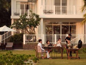 富国Premier Village Phu Quoc Resort Managed by Accor的一群人坐在房子前面的桌子上