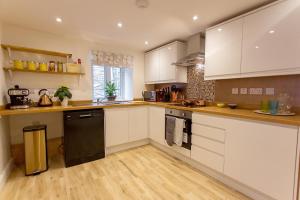 彭里斯Joiners cottage的厨房配有白色橱柜和黑色洗碗机