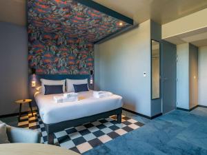 第戎ibis Styles Dijon Sud Domaine De Beauregard 21600 Longvic的卧室配有一张大床,墙上挂有绘画作品