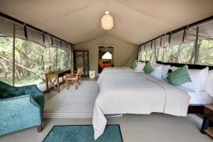 塔勒克Olkinyei Mara Tented Camp的卧室配有一张床和一张桌子及椅子
