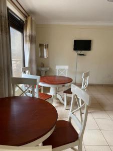 NamugongoTwinkle Blue Inn的客厅配有2张桌子和椅子以及电视