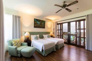 沙努尔Villa Nesanur - Comfortable & Spacious Beachside Sanur的一间卧室配有一张床、一把椅子和吊扇