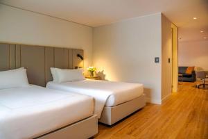 波哥大NH波哥大帕维永罗伊尔酒店 的走廊的客房内设有两张白色的床
