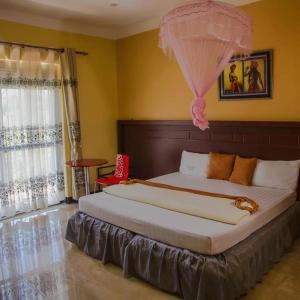 WakisoKakiri Gardens and Hotel的一间卧室配有一张大床,上面有粉红色的雨伞