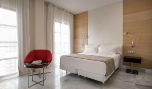 科尔多瓦NH收藏阿米斯塔德科尔多瓦酒店的一间卧室配有一张床和一张红色椅子