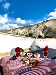 HinojaresCasa Rural Caballeriza的配有食品和酒杯的野餐桌,享有山景