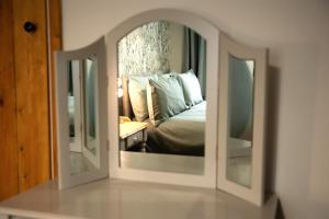 水上伯顿2 Bedroom Charming & Luxury Malt Cottage, Garden, Netflix, Free Parking的镜子中卧室的反射,镜子中的床