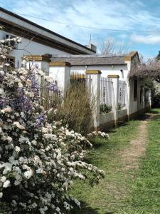 查斯科穆斯Hostería Casa de Campo的房屋前的白色围栏和鲜花