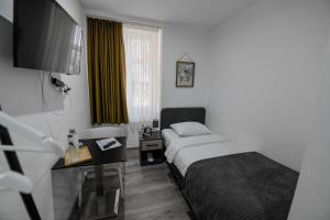 拉绍德封法国酒店的一间卧室配有一张床、一张书桌和一台电视