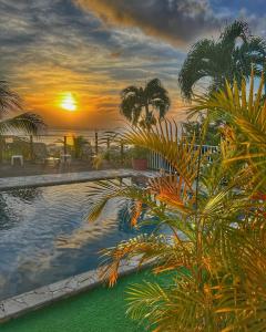 巴斯特尔Résidence Paradis Tropical的棕榈树游泳池的日落