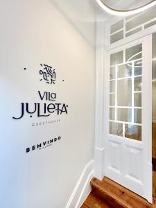科英布拉Vila Julieta Guesthouse的一间白色墙壁的房间,上面有Vu judica标志