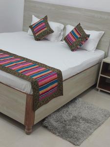 瓦拉纳西5 PETALS的一张带白色床单和彩色枕头的床