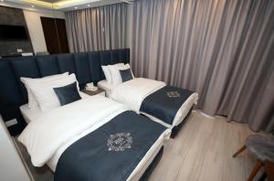 拜特龙Batroun boutique suites的配有窗帘的酒店客房内的两张床