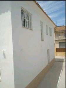 赫雷斯-德拉弗龙特拉Casa en Jerez con patio cerca de la playa y de la sierra的两扇窗户的白色建筑