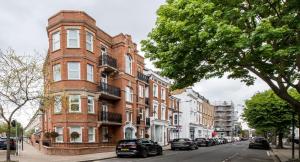 伦敦Kensington Olympia Apartment, Breakfast的一座红砖建筑,前面停有汽车